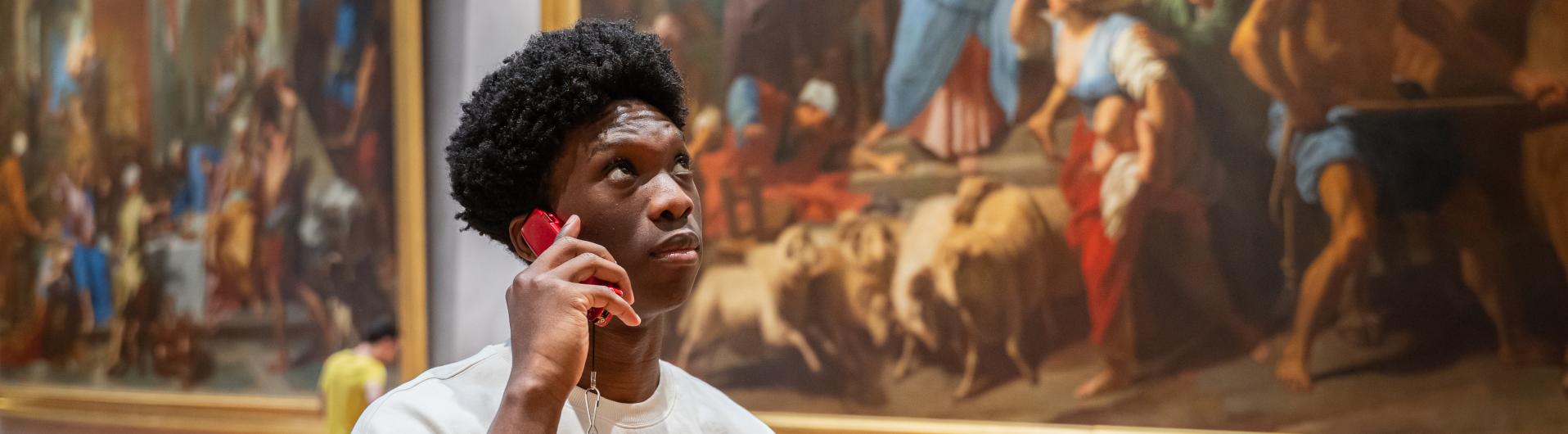 Kevin Amassouga (homme) qui pose avec un audioguide dans la salle des grands formats. 